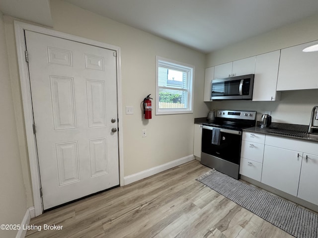 1254 S Preston St, Louisville, KY 40217 - kitchen with stainless steel appliances, dark countertops, a sink, and white cabinetry