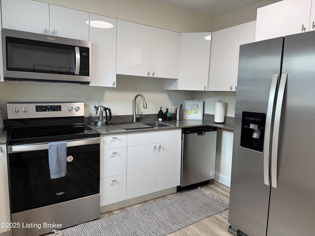 1254 S Preston St, Louisville, KY 40217 - kitchen featuring stainless steel appliances, white cabinetry, a sink, and light wood-style floors