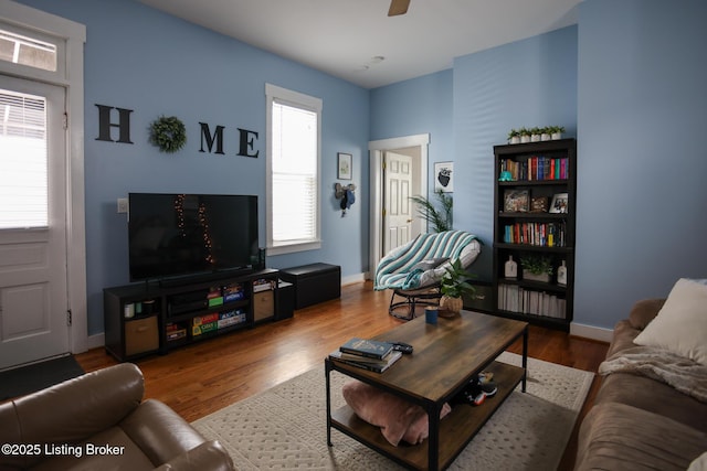 living area with healthy amount of natural light, a ceiling fan, wood finished floors, and baseboards