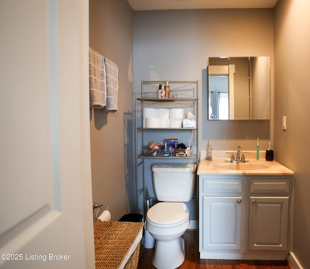 bathroom with wood finished floors, toilet, and vanity