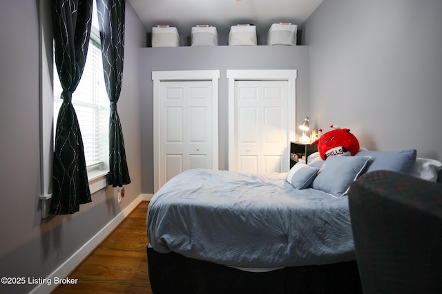 bedroom with multiple closets, baseboards, and wood finished floors