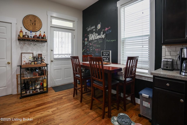 dining space featuring healthy amount of natural light, light wood-style floors, and a bar