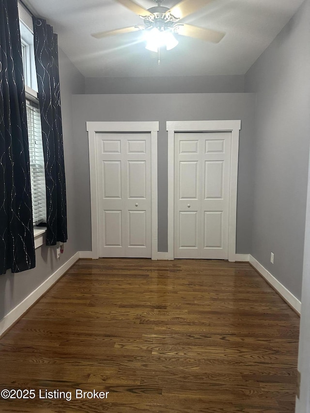 827 Mulberry St, Louisville, KY 40217 - unfurnished bedroom featuring multiple closets, dark wood-style floors, baseboards, and a ceiling fan