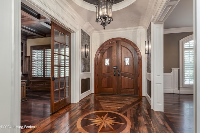 entrance foyer featuring a decorative wall, dark wood-type flooring, crown molding, wainscoting, and a chandelier