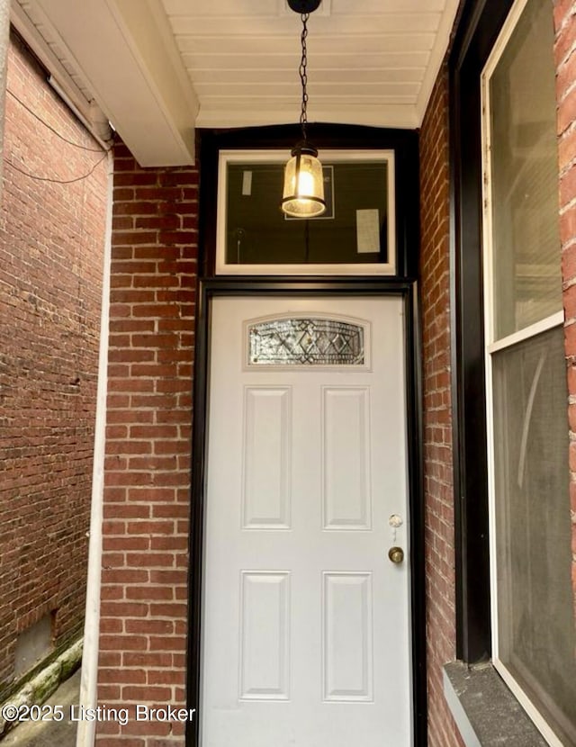 doorway to property with brick siding and a porch