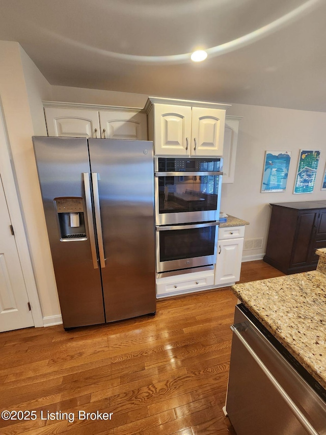 7201 Creekton Dr, Louisville, KY 40241 - kitchen featuring stainless steel appliances, light wood-type flooring, white cabinets, light stone countertops, and baseboards