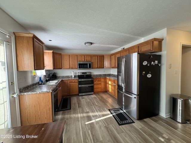8005 Grandmeadow Ln, Louisville, KY 40258 - kitchen with stainless steel appliances, a sink, light wood-style floors, a textured ceiling, and brown cabinets