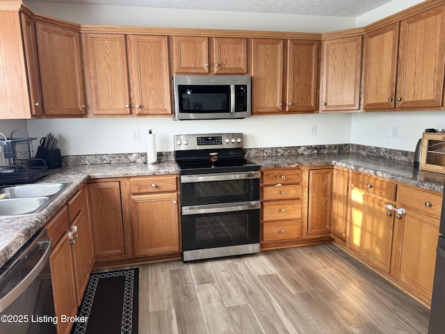 8005 Grandmeadow Ln, Louisville, KY 40258 - kitchen featuring appliances with stainless steel finishes, brown cabinets, and light wood-style floors