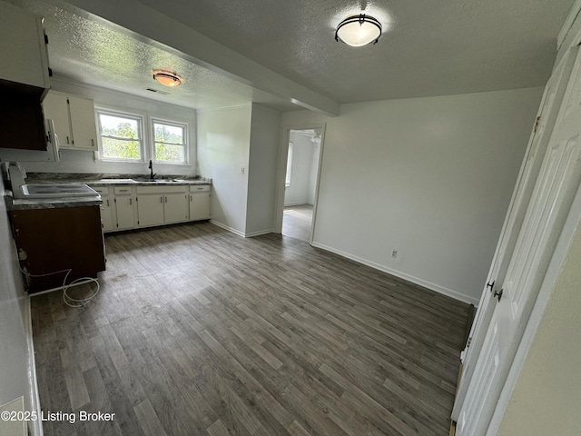76 Bethel Church Rd, Brandenburg, KY 40108 - kitchen with a textured ceiling, white cabinets, dark wood-style flooring, a sink, and baseboards