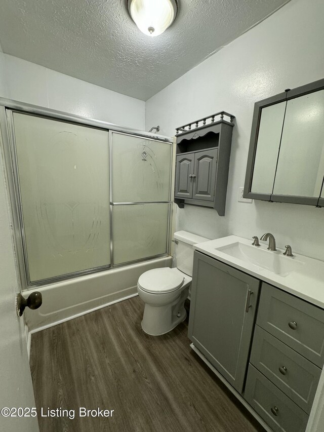 76 Bethel Church Rd, Brandenburg, KY 40108 - bathroom featuring wood finished floors, a textured ceiling, vanity, shower / bath combination with glass door, and toilet