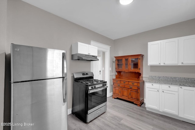 611 E Hill St, Louisville, KY 40217 - kitchen with stainless steel appliances, under cabinet range hood, light wood-style flooring, light stone counters, and white cabinetry