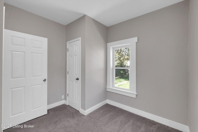611 E Hill St, Louisville, KY 40217 - unfurnished bedroom with dark colored carpet and baseboards