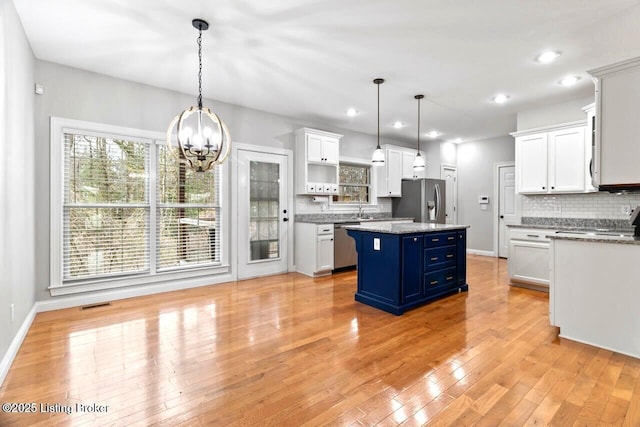 135 N Parkside Dr, Bardstown, KY 40004 - kitchen with appliances with stainless steel finishes, blue cabinetry, a chandelier, white cabinetry, and tasteful backsplash