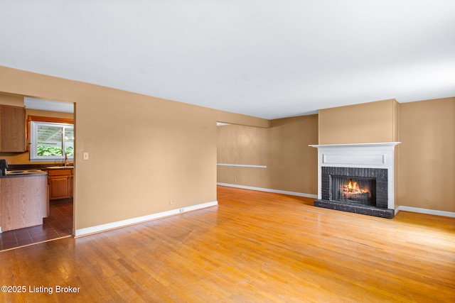 118 Guthrie Dr, Bardstown, KY 40004 - unfurnished living room with light wood-style flooring, a brick fireplace, and baseboards