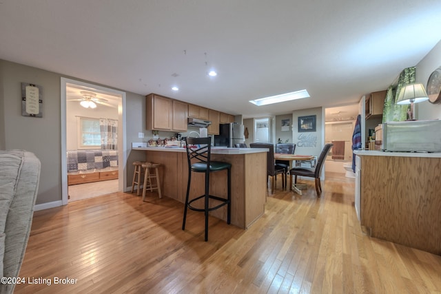 3085 Centerview Rough River Ln, Hudson, KY 40145 - kitchen with freestanding refrigerator, light wood-type flooring, under cabinet range hood, a peninsula, and a kitchen bar