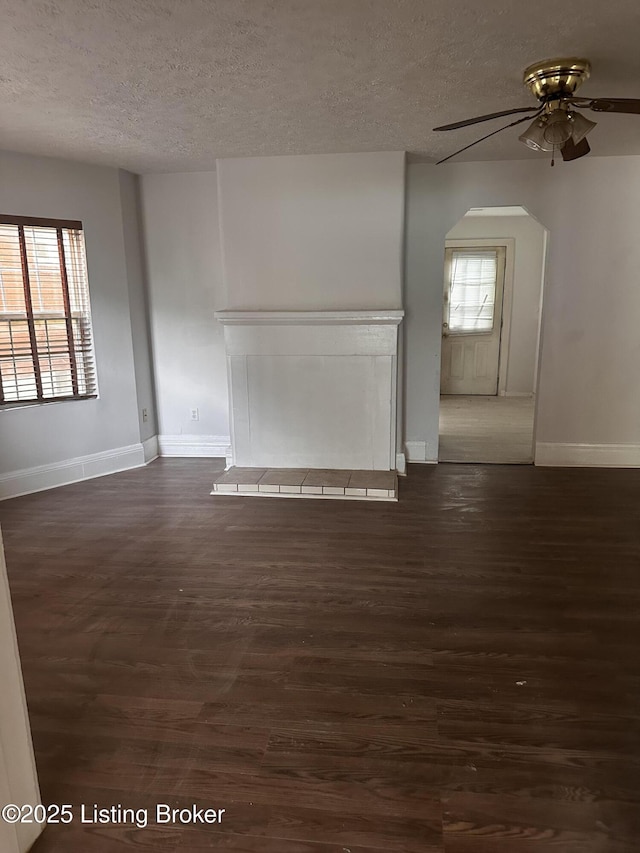 2325 Bolling Ave, Louisville, KY 40210 - empty room featuring a textured ceiling, baseboards, ceiling fan, dark wood finished floors, and arched walkways