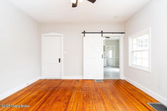 1205 Fischer Ave, Louisville, KY 40204 - unfurnished bedroom with wood-type flooring, a barn door, baseboards, and ceiling fan