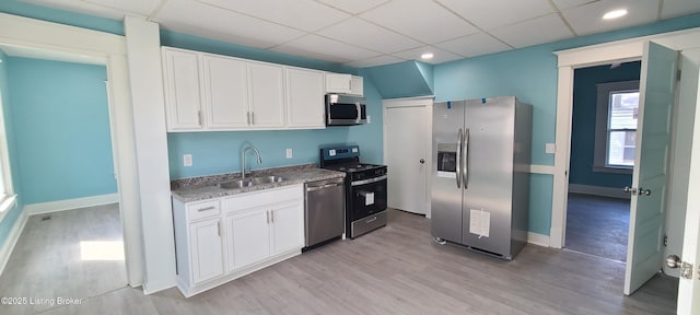 1033 Lynnhurst Ave, Louisville, KY 40215 - kitchen featuring stainless steel appliances, a sink, a drop ceiling, white cabinets, and light wood-type flooring