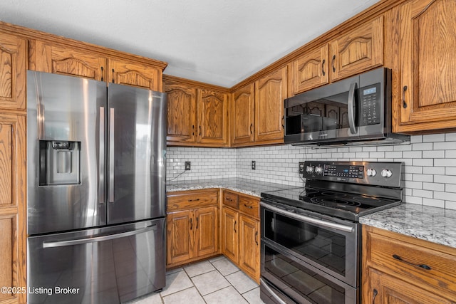 916 Winchester Blvd, Elizabethtown, KY 42701 - kitchen with appliances with stainless steel finishes, brown cabinetry, light tile patterned floors, and decorative backsplash