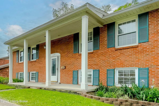 property entrance featuring a porch and brick siding