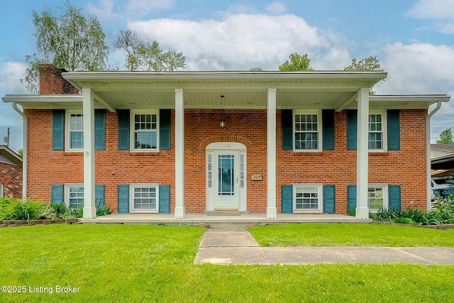 bi-level home featuring a porch, a chimney, a front yard, and brick siding