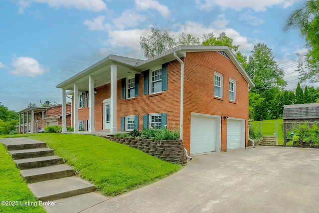 raised ranch with an attached garage, driveway, brick siding, and covered porch