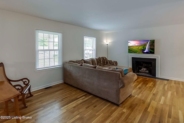 living area featuring light wood-type flooring, a fireplace, and baseboards