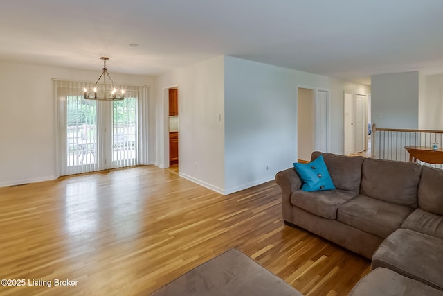 living area with a chandelier, light wood-type flooring, and baseboards