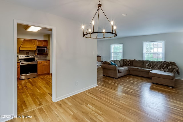 living area with light wood-type flooring, a chandelier, and baseboards