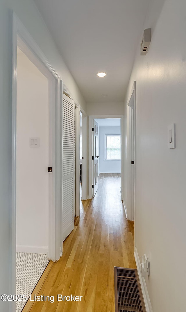 corridor with baseboards, light wood-type flooring, and recessed lighting