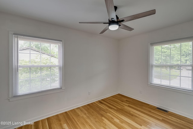 empty room featuring plenty of natural light, baseboards, a ceiling fan, and light wood-type flooring
