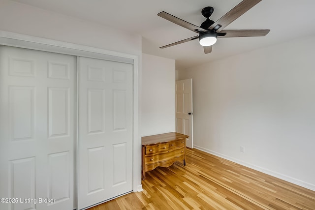 unfurnished bedroom featuring light wood-style flooring, a closet, baseboards, and ceiling fan
