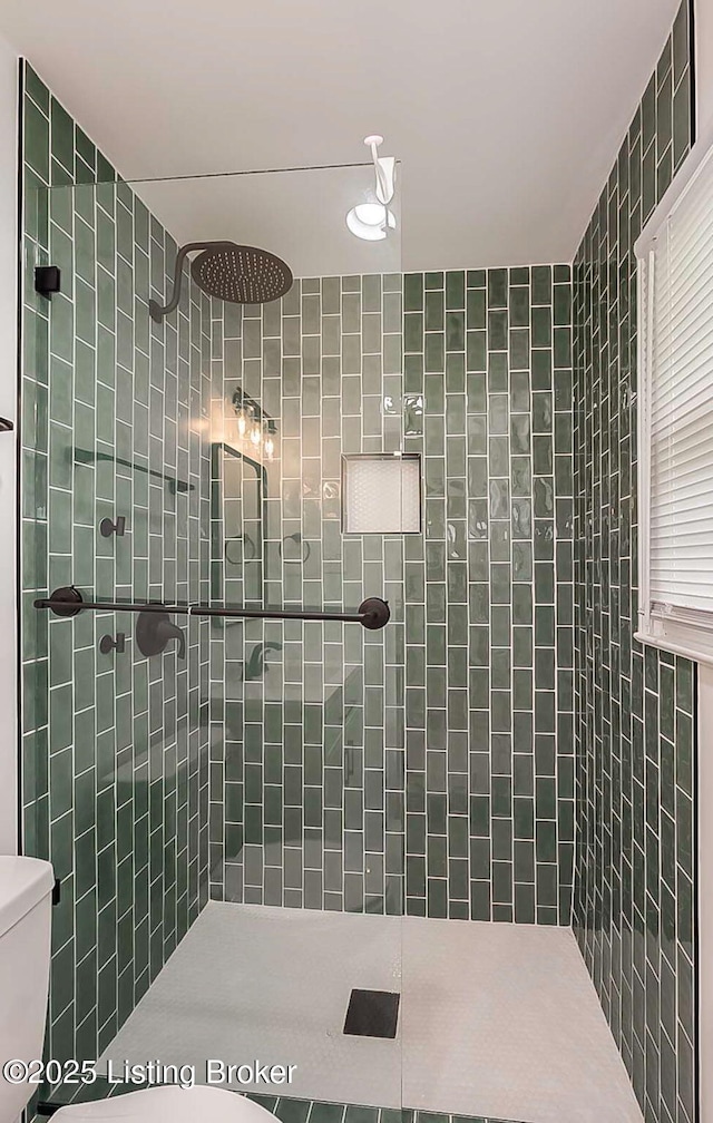 full bath with toilet and a tile shower