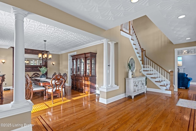 entryway featuring wood finished floors, decorative columns, baseboards, an ornate ceiling, and recessed lighting