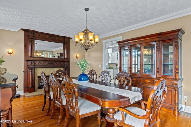 dining room with a chandelier, light wood-style flooring, crown molding, and baseboards