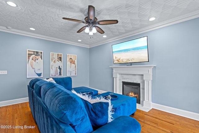 living area featuring ceiling fan, a fireplace with flush hearth, recessed lighting, wood finished floors, and baseboards