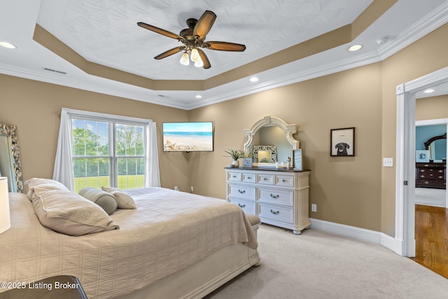 bedroom with a tray ceiling, crown molding, recessed lighting, baseboards, and light carpet