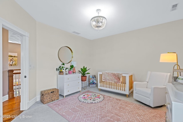 bedroom featuring a chandelier, a crib, baseboards, and carpet floors