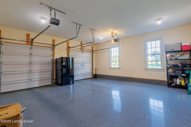 garage with black fridge with ice dispenser, a garage door opener, and baseboards