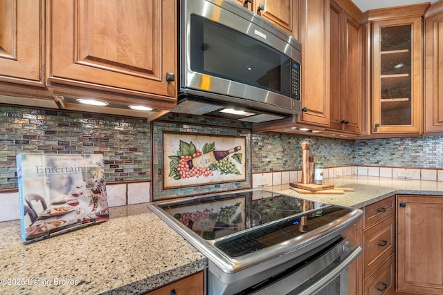 10304 Spring Meyer Rd, Louisville, KY 40223 - kitchen with stainless steel appliances, brown cabinetry, decorative backsplash, and light stone countertops
