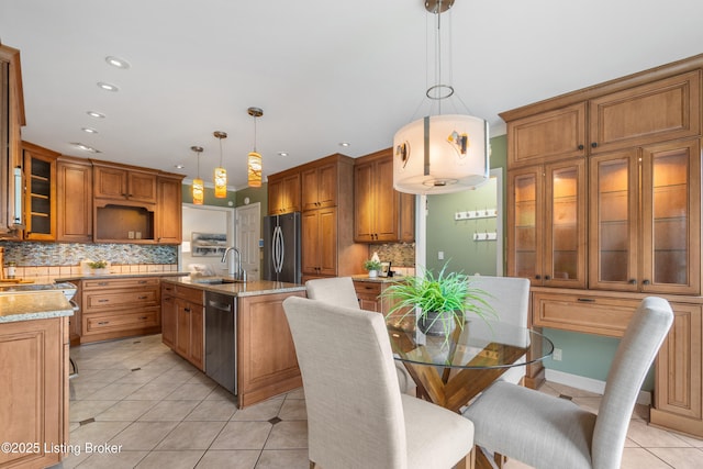 10304 Spring Meyer Rd, Louisville, KY 40223 - kitchen featuring appliances with stainless steel finishes, light tile patterned floors, a center island with sink, backsplash, and light stone counters