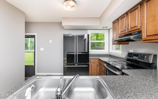 3009 Huberta Dr, Louisville, KY 40216 - kitchen with freestanding refrigerator, stainless steel range with electric stovetop, under cabinet range hood, brown cabinetry, and dark countertops