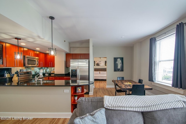 604 S 3rd St Unit 803, Louisville, KY 40202 - kitchen featuring stainless steel appliances, dark countertops, light wood finished floors, a peninsula, and healthy amount of natural light