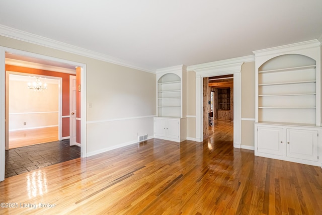 3920 Elfin Ave, Louisville, KY 40207 - unfurnished room featuring a chandelier, built in shelves, baseboards, ornamental molding, and wood finished floors