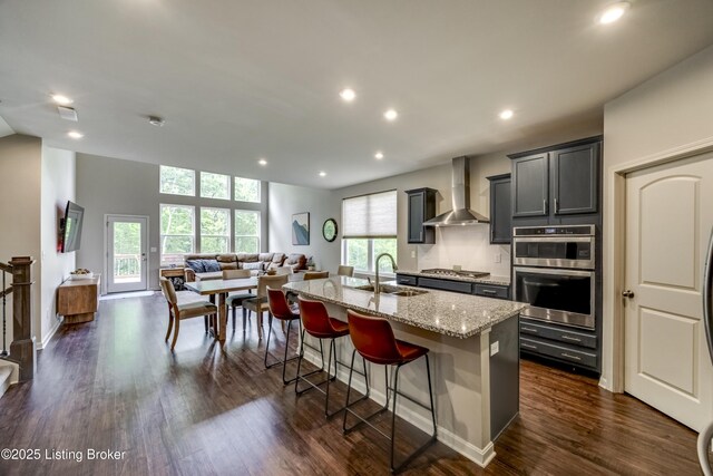 3928 Creek Meadow Dr, La Grange, KY 40031 - kitchen featuring wall chimney range hood, open floor plan, stainless steel appliances, an island with sink, and a sink