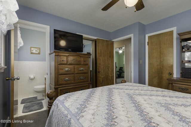7407 Beahl Blvd, Louisville, KY 40258 - bedroom featuring ensuite bath, ceiling fan, tile walls, and wainscoting