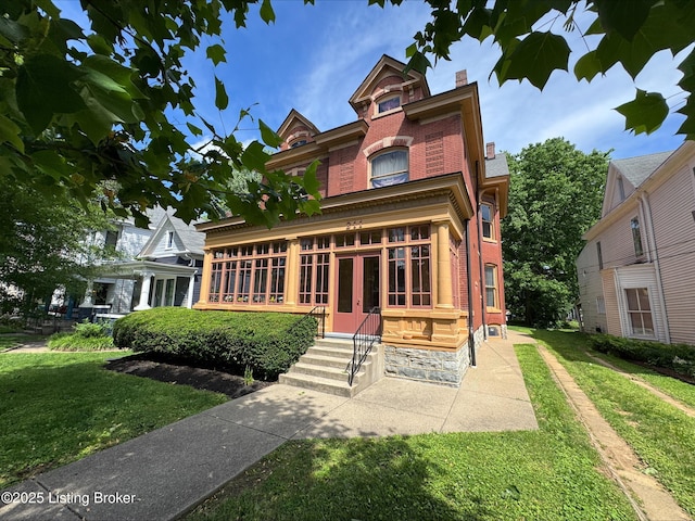 211 Haldeman Ave, Louisville, KY 40206 - victorian house with brick siding, a front yard, a chimney, and french doors