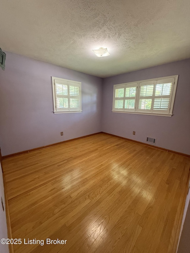 7406 Arapaho Dr, Louisville, KY 40214 - empty room with light wood-style flooring, healthy amount of natural light, a textured ceiling, and baseboards