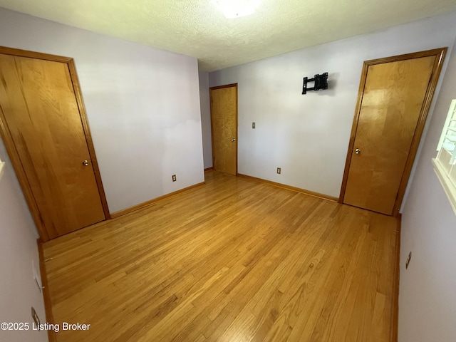 7406 Arapaho Dr, Louisville, KY 40214 - unfurnished bedroom with light wood-style floors, a textured ceiling, and baseboards