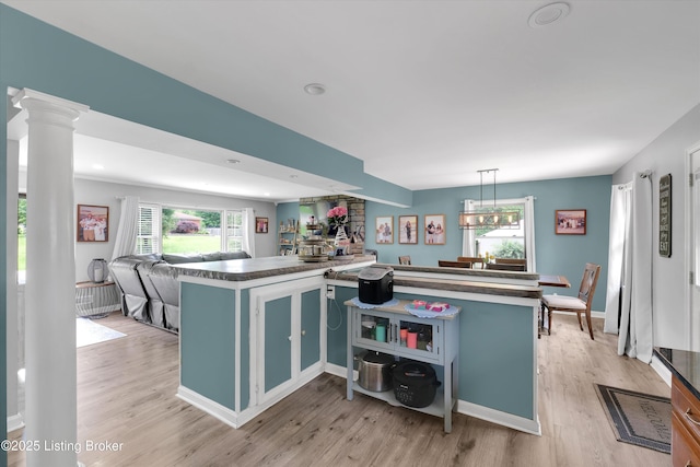 9926 Silverwood Ln, Louisville, KY 40272 - kitchen with light wood-style flooring, dark countertops, open floor plan, decorative columns, and a kitchen island